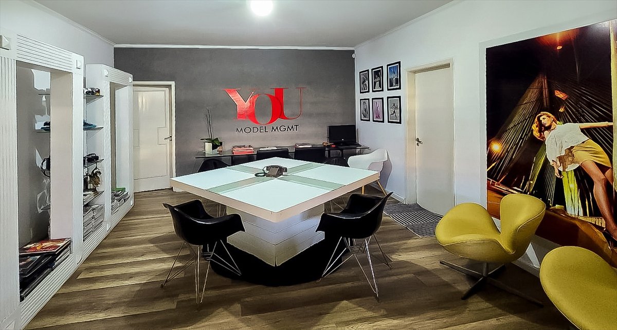 Sala de reunião da YOU Models, com a marca na parede